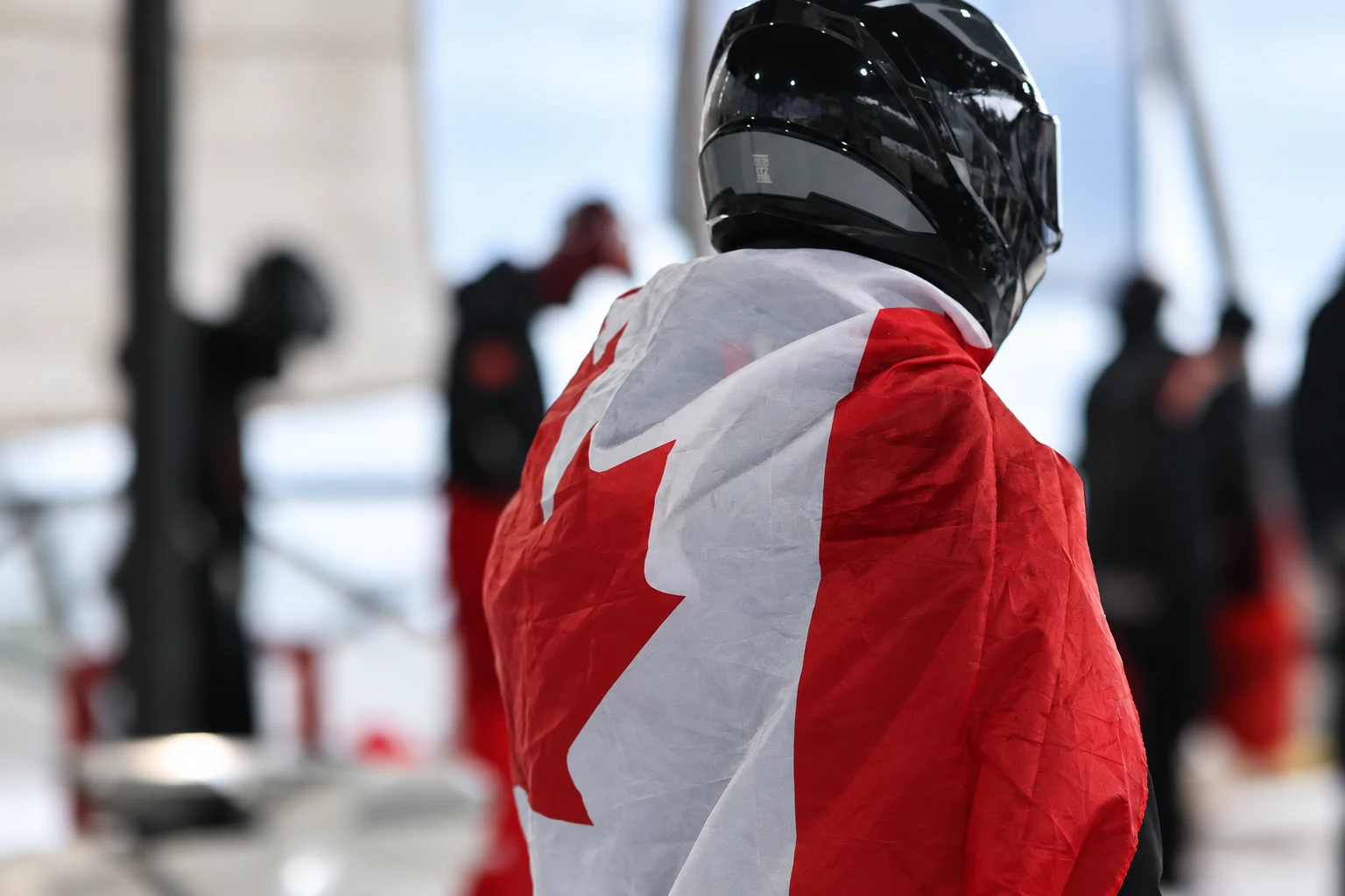 Helmeted athlete wrapped in a Canadian flag at the bobsled venue
